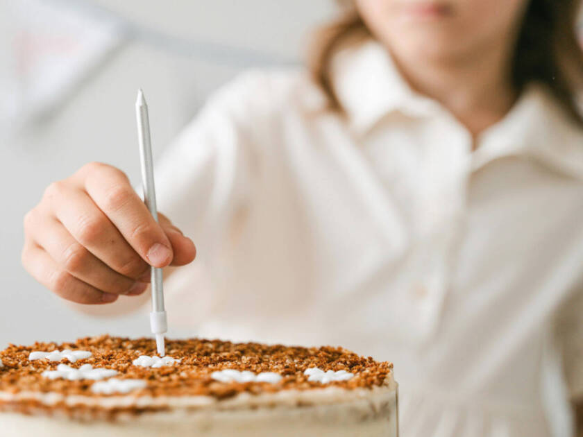Nainen asettaa kakkukynttilää juhlakakun päälle.